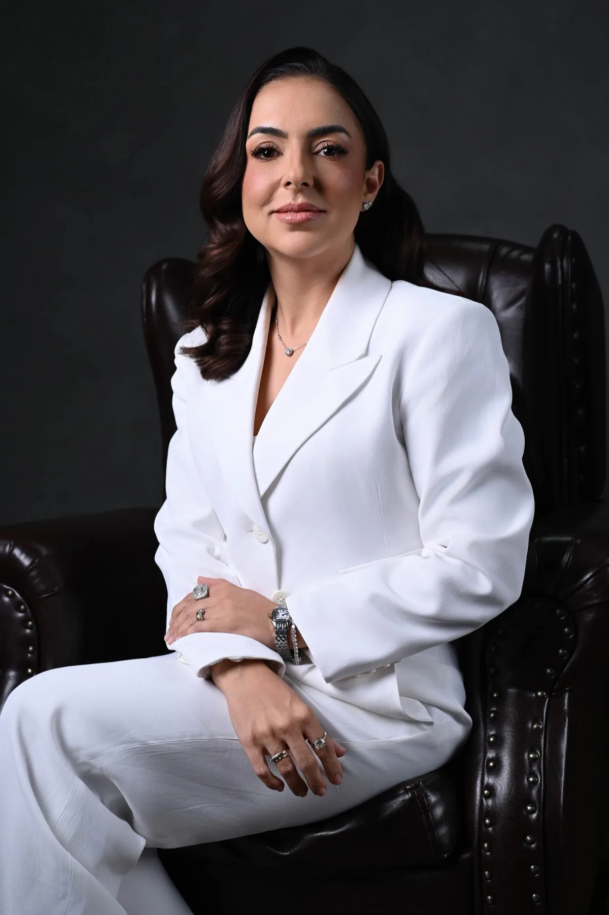 Rafaela Félix sentada em uma poltrona, de terno branco